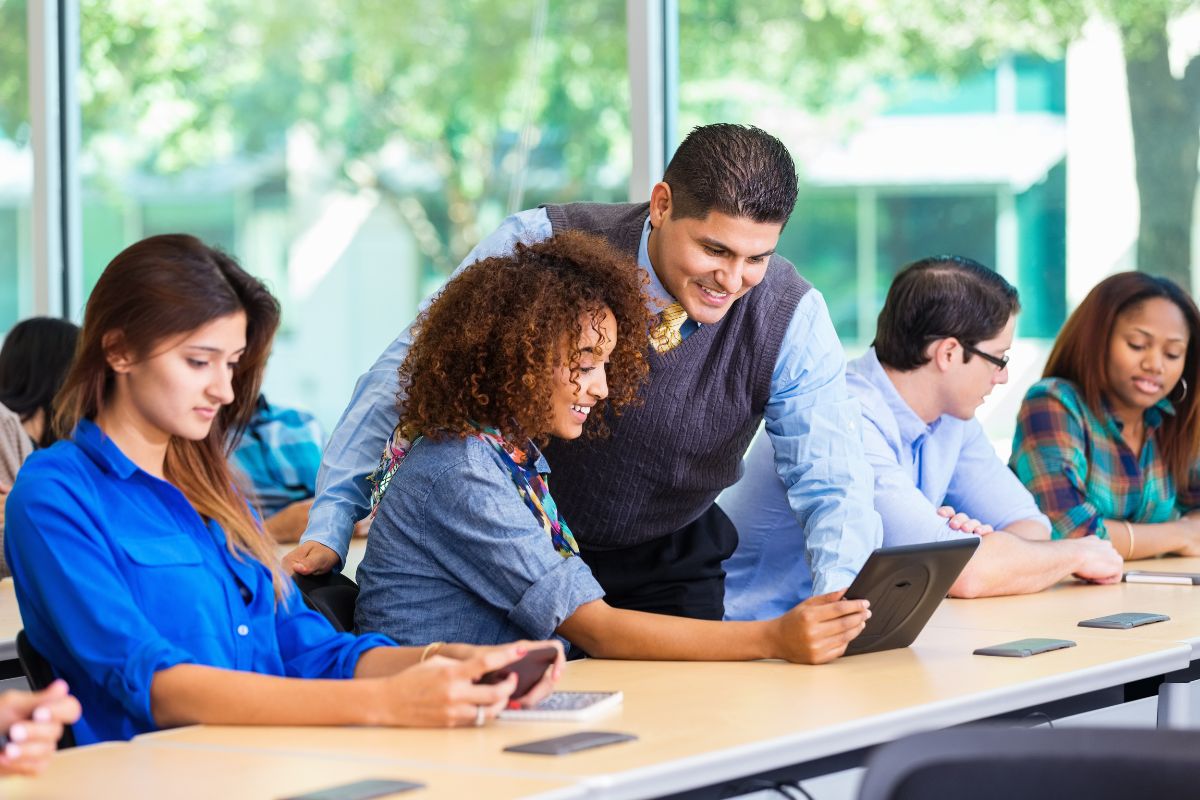 An educator reviews something on a tablet with their student in a classroom