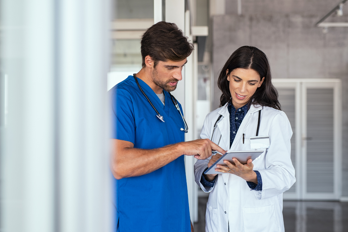 A pair of medical professionals reviewing a digital file on a tablet